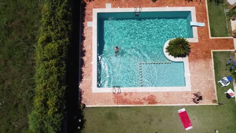 Vista-Aérea-De-Un-Hombre-Saltando-A-Una-Piscina-De-Lujo-Durante-El-Verano