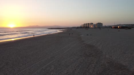 Vista-Aérea-De-Personas-Disfrutando-Del-Atardecer-En-La-Playa-En-Costa-Da-Caparica,-Portugal