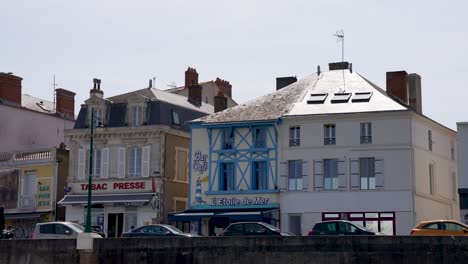 Restaurants-and-a-Tabaco-shop-seen-from-the-shore-with-cars-passing,-View-from-boat