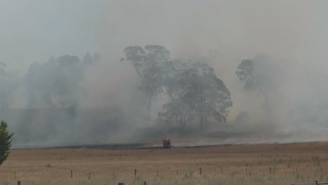 Ein-Einsamer-Feuerwehrwagen-Sprüht-Wasser-Auf-Den-Rand-Eines-Riesigen-Grasfeuers,-Um-Die-Ausbreitung-An-Einem-Warmen,-Windigen-Tag-Zu-Kontrollieren