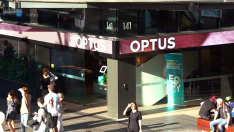 Tienda-Insignia-De-Optus-En-El-Centro-Comercial-Queen-Street-De-Brisbane,-Repleta-De-Grandes-Multitudes-De-Estudiantes-Y-Peatones-En-El-Centro-De-La-Plaza-En-El-Distrito-Central-De-Negocios-Durante-El-Día