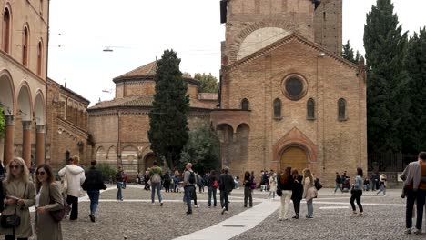 Tourists-Walking-Across-Piazza-Santo-Stefano-With-Basilica-of-Santo-Stefano-In-The-Background-In-Bologna