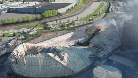 Aerial-above-collapsed-and-burning-sugar-storage-facility-with-fire-engines-in-the-background