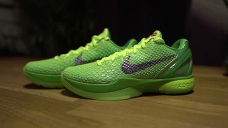 Grüne-Nike-Kobe-6-Protro-Grinch-2020-Schuhe,-Gefilmt-Auf-Einem-Braunen-Tisch-Mit-Dunklem-Hintergrund