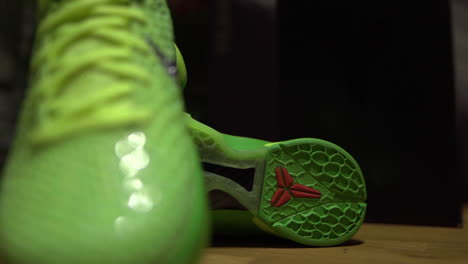 Zapatos-Nike-Kobe-6-Protro-Grinch-2020-Verdes-Filmados-Sobre-Una-Mesa-Marrón-Con-Fondo-Oscuro