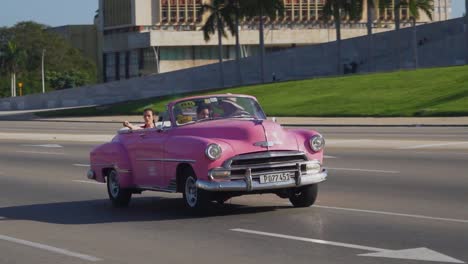 Toma-De-Seguimiento-De-Turistas-Viajando-En-Un-Auto-Viejo-En-La-Habana,-Cuba.