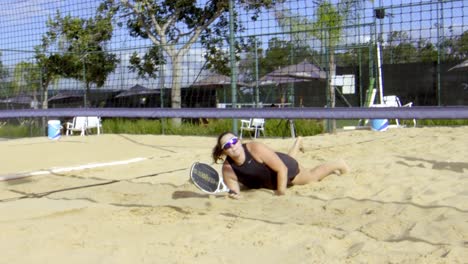 Jugadora-De-Tenis-De-Playa-Dando-Un-Salto-En-La-Arena-Para-Jugar-A-Golpear-La-Pelota,-Salvada-épica,-Captura,-Caída,-Mentalidad-Fuerte-En-La-Competencia,-Ojos-En-El-Precio,-Ganador,-Juego-En-Equipo-Femenino,-Torneo-De-Ocio-Soleado