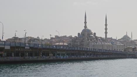 Galata-bridge-fish-restaurants-Eminonu,-mosque-city-skyline-Golden-Horn