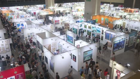Wide-view-of-Chinese-visitors-attending-an-art-fair-show-where-art-exhibitors-sell-paintings-and-sculptures-to-visitors,-art-enthusiasts,-and-collectors
