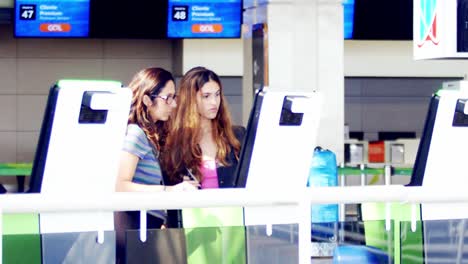 Madre-E-Hija-Registrándose-En-Un-Quiosco-De-Autoservicio-En-El-Aeropuerto,-Cámara-Lenta