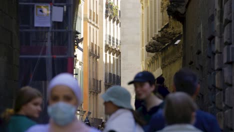 Pont-del-Bisbe,-Barcelona,-with-tourists-walking-through-narrow-street-in-Barri-Gothic-Quarter