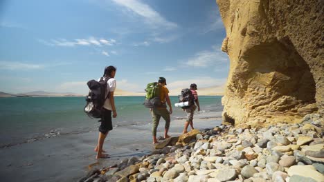 Campistas-Caminando-Por-La-Playa-De-Arena-Notando-Una-Enorme-Formación-Rocosa,-California