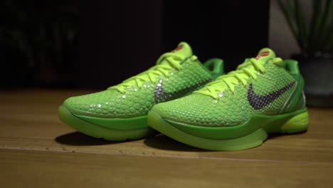 Zapatos-Nike-Kobe-6-Protro-Grinch-2020-Verdes-Filmados-Sobre-Una-Mesa-Marrón-Con-Fondo-Oscuro