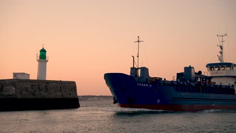 General-cargo-French-ship-CASAM-IV-entering-its-home-port-at-dusk,-Pan-left-follow-shot