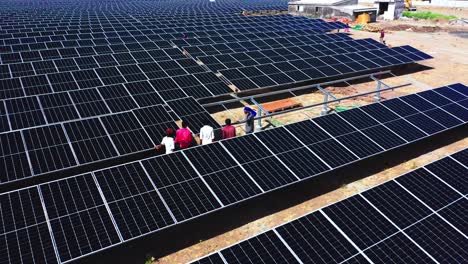 close-up-view-of-laborers-transporting-solar-modules-for-fitting-is-followed-by-an-aerial-drone-camera