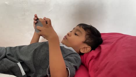 A-4-year-old-asian-boy-playing-games-on-his-smartphone-while-lying-in-bed