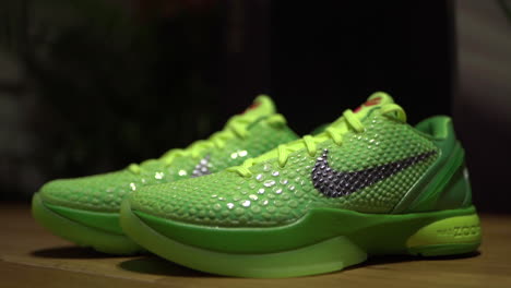 Green-Nike-Kobe-6-Protro-Grinch-2020-shoes-filmed-on-a-brown-table-with-dark-background