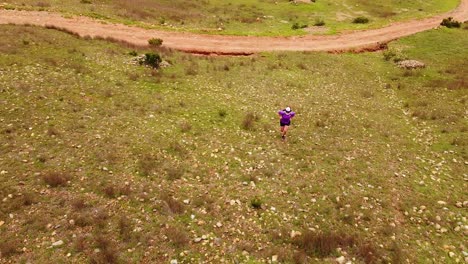 Lone-Girl-With-Backpack-Climbing-On-A-Rocky-Hill-Of-Mountains-In-Summer