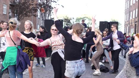 Los-Jóvenes-Asistentes-Al-Festival-Y-A-La-Fiesta-Disfrutan-De-La-Vida-En-Una-Fiesta-Callejera-Al-Aire-Libre-Bailando-Juntos,-Unidos-Como-Amigos.