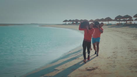 A-Group-Of-Athletes-Running-By-The-Shore-carrying-sandbags-at-The-North-Coast---Slow-Motion