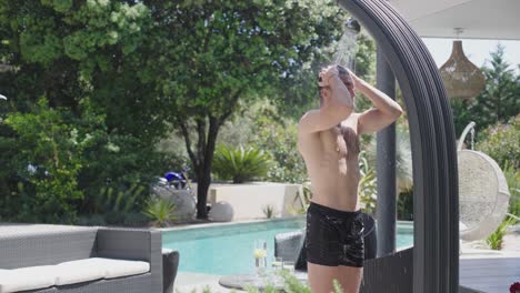 Un-Apuesto-Hombre-Musculoso-Duchándose-En-La-Terraza-De-Su-Moderno-Y-Lujoso-Jardín-Con-Una-Gran-Piscina-Y-Salón-Al-Aire-Libre