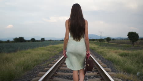 Modelo-En-Vestido-De-Verano-Caminando-Lentamente-En-La-Vía-Del-Tren---Tiro-De-Seguimiento-Medio-En-Cámara-Lenta