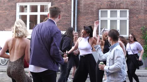 Los-Jóvenes-Asistentes-Al-Festival-Y-A-La-Fiesta-Disfrutan-De-La-Vida-En-Una-Fiesta-Callejera-Al-Aire-Libre-Bailando-Juntos,-Unidos-Como-Amigos.