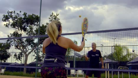 Ein-Mann-Und-Eine-Frau-Spielen-Nachmittags-Gemeinsam-Tennis-An-Einem-Meeresstrand