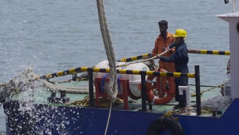 Schlepperdeckmann-Greift-Mit-Einem-Haken-Nach-Der-Festmacherleine-Eines-Anlegenden-Schiffes