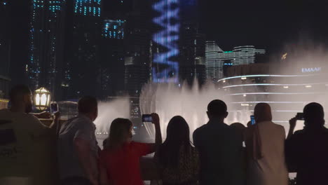 Tourists-with-smartphones-watching-the-Dubai-Fountain-show-in-May-2021-in-UAE-in-front-of-the-Burj-Khalifa-at-night