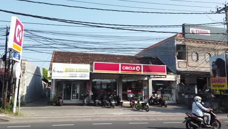 Circle-K-Store-Entrance-in-Sanur-Bali-Indonesia,-Street-Traffic-with-Cars-and-Scooters-during-Daylight,-Convenience-Store,-Establishing-Shot,-Neighborhood