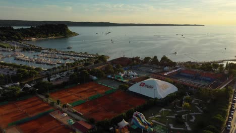 Drone-Aéreo-Hacia-Adelante-Vista-Aérea-Lenta-De-Portoroz-Con-Barcos-En-El-Mar-A-La-Luz-Amarilla-Del-Atardecer,-Eslovenia