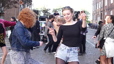 Los-Jóvenes-Asistentes-Al-Festival-Y-A-La-Fiesta-Disfrutan-De-La-Vida-En-Una-Fiesta-Callejera-Al-Aire-Libre-Bailando-Juntos,-Unidos-Como-Amigos.