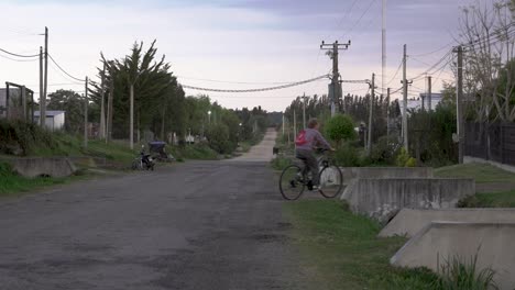 Elderly-woman-riding-a-bicycle-in-an-old-neighborhood-of-a-rural-town