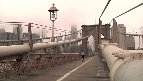 Frau-Rennt-An-Einem-Nebligen-Morgen-Auf-Der-Brooklyn-Bridge-In-New-York-Vorbei