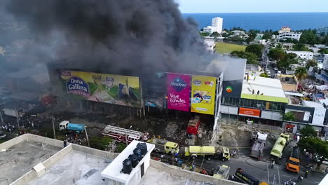 Luftaufnahme,-Statisch,-Drohnenaufnahme-Von-Feuerwehrautos,-Vor-Einem-Brennenden-Lagerhaus,-Dunkler-Rauch-Steigt-Auf,-In-Der-Stadt-Santo-Domingo,-Dominikanische-Republik