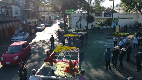 Vista-De-Pájaro-De-Dolly-En-Seguimiento-Del-Carnaval-De-Iztapalapa-Grupo-De-Personas-Portando-Arreglos-Florales-Gigantes,-Cdmx,-México