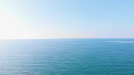 Aerial,-drone-shot,-of-a-man-sitting-on-log,-looking-out-on-the-Black-sea,-during-golden-hour,-in-Kobuleti,-Adjara,-Georgia