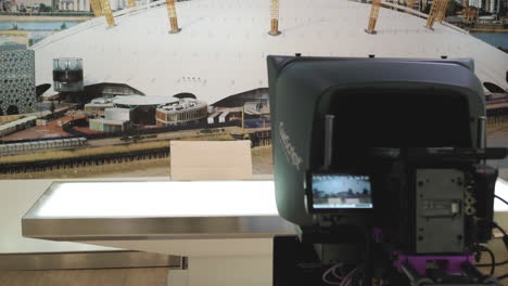 Empty-news-desk-in-a-television-studio-TV-news-room-with-camera-and-teleprompter-in-the-foreground