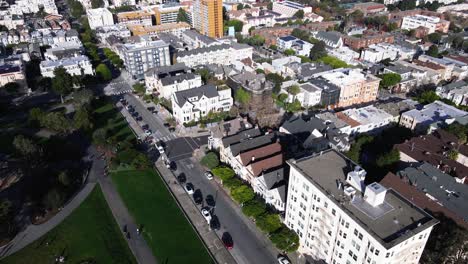 Las-Imágenes-De-Drones-Presentan-Una-Vista-Serena-De-Las-Siete-Damas-Pintadas-De-San-Francisco,-Casas-Victorianas-Icónicas,-En-Contraste-Con-El-Vibrante-Paisaje-Urbano-Y-La-Exuberante-Vegetación-Del-Parque-Alamo-Square.