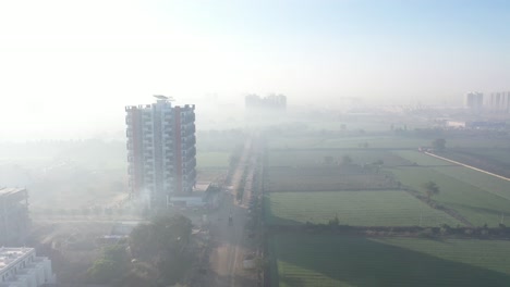 aerial-drone-shot-drone-camera-is-going-to-the-back-side-where-there-are-lots-of-surrounding-large-farms-and-residential-houses-and-there-is-a-building-construction-going-on