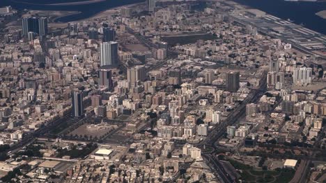 The-aerial-drone-is-moving-towards-the-camera-showing-many-large-complexes-and-buildings-and-many-vehicles-driving-on-the-road