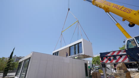 Unidad-De-Vivienda-Modular-Colgando-De-Una-Grúa-Colocada-En-Su-Posición-En-El-Sitio-De-Construcción