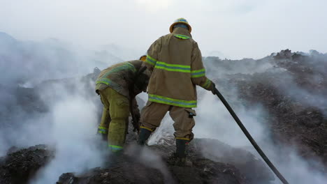 Dos-Bomberos-Luchando-Contra-Un-Incendio-Forestal,-En-Terreno-Lleno-De-Humo,-Día-Nublado,-En-República-Dominicana