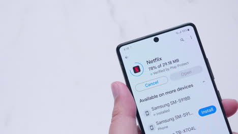 Close-up-of-an-individual-who-is-enabling,-updating,-then-installing-the-application-of-Netflix-to-a-smart-mobile-phone