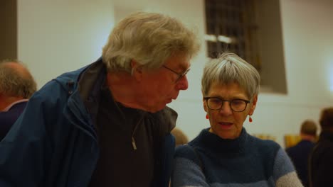 Una-Pareja-De-Ancianos-De-Pelo-Gris-Con-Gafas-Negras-Asintiendo-Y-Hablando