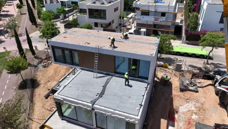 Vista-Aérea-De-Arriba-Hacia-Abajo-De-Una-Casa-Modular-Prefabricada-Con-Trabajadores-Trabajando-En-El-Sitio-De-Construcción