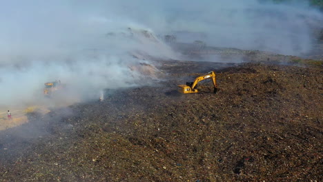 Luftaufnahme,-Verfolgung,-Drohnenaufnahme-Der-Feuerwehr,-Die-Einen-Bagger-Zum-Löschen-Eines-Waldbrandes-Einsetzt,-Rauch-Steigt-In-Zerstörter-Natur-Auf,-Sonniger-Tag,-In-Der-Dominikanischen-Republik