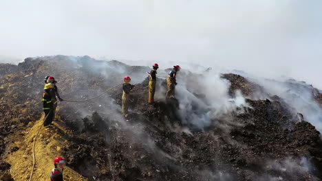 Aerial,-tracking,-drone-shot-of-firefighters-fighting-a-wildfire,-smoke-rising-in-burnt-nature,-on-a-sunny-day,-in-the-Amazon-jungle,-Brazil,-South-America