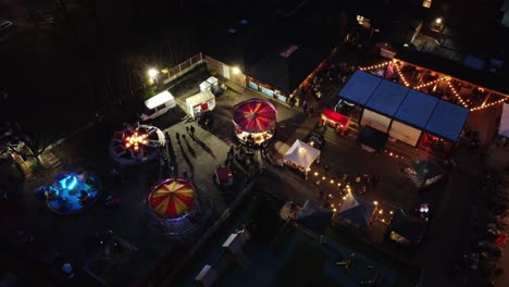 Parque-De-Atracciones-Navideño-Iluminado-En-El-Aparcamiento-Del-Pub-Del-Barrio-Por-La-Noche-Vista-Aérea